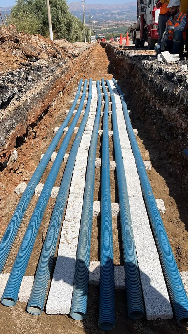 Açık kanalda yan yana döşenmiş koruge borular ve beton koruma plakaları