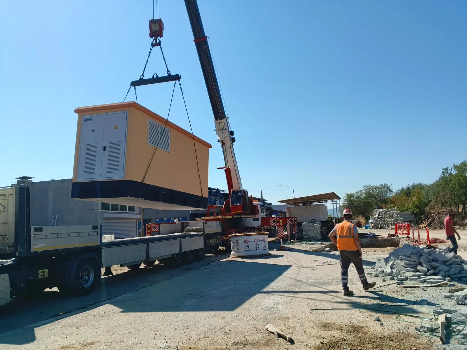 Beton köşk kamyondan vinçle alınıyor; saha ekibi çevrede güvenlik alıyor